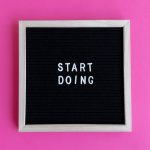Black letter board with 'Start Doing' motivational text on bright pink background.