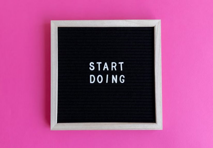 Black letter board with 'Start Doing' motivational text on bright pink background.